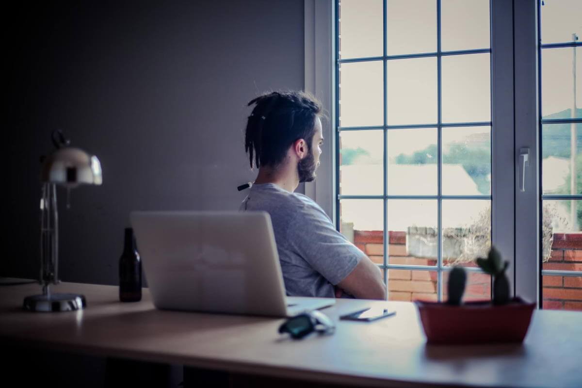 Rather than working at his laptop on the desk, this guy is facing the other direction, aimlessly staring out the window. This image is here to represent someone who is feeling disengaged at work.