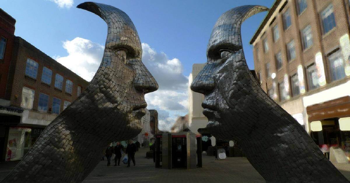 Leadership vs Management: A picture of sculpture of two metal faces, facing each other, two feet apart. From Medford, England. In this case, the faces are to represent Leadership and Management.