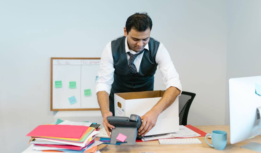 A man dressed in business casual is pictured packing up his desk to leave his job during The Great Resignation 2021.