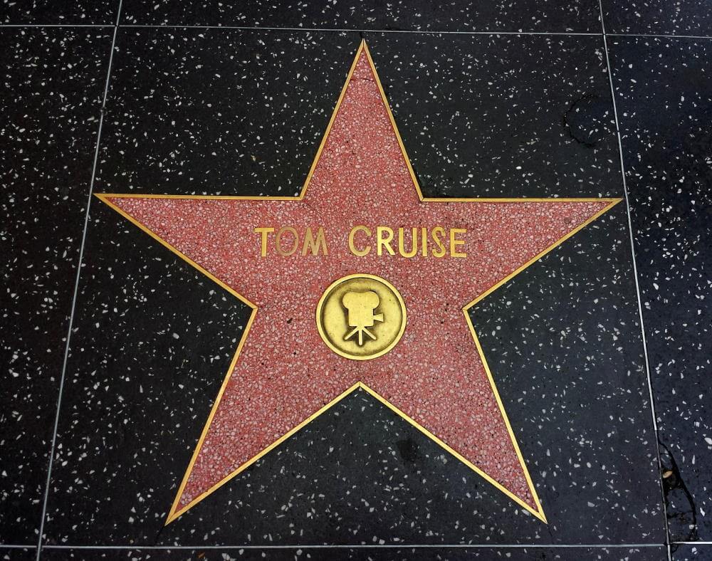 This article is about Tom Cruise's rant on the set of Mission Impossible 7, so this is a picture of his star on the Hollywood Walk of Fame. The sidewalk background is black marble with specks of silver glitter, the board of the star, Tom Cruise's name, and camera icon are gold, and the interior of the star is red.