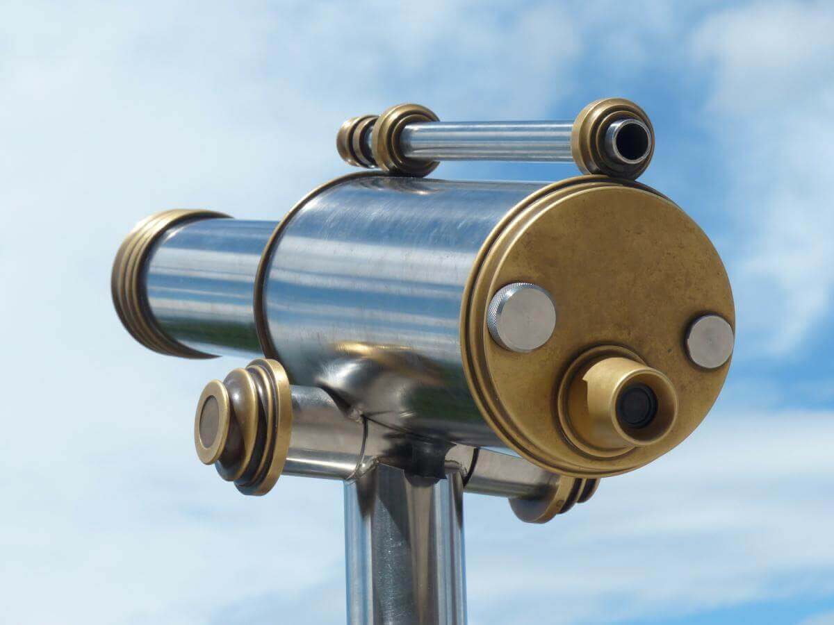 An image of a telescope aiming off into the great blue yonder. It's the type of telescope used on observation decks to look at the surroundings. In this case, the telescope is symbolic of vision.