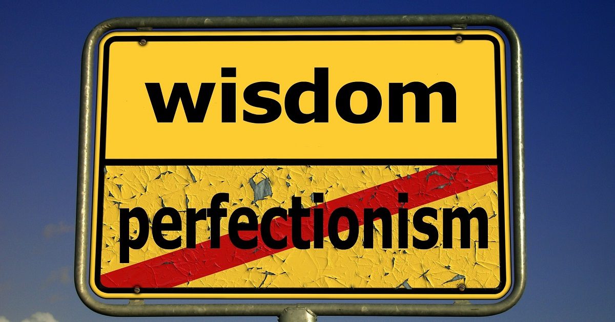 A picture of a yellow sign with black letter. The top section of the sign says "wisdom". The bottom section of the sign says "perfectionism", with a red slash through it. The wisdom portion of the sign is in great shape with new paint. The perfectionism portion of the sign has peeling paint and looks bad.